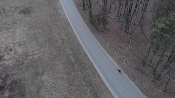 Ormanda bisikletle gezen profesyonel bisikletçilerin hava görüşü. Kasklı bir triatloncu, spor kıyafetleri içinde pedal çeviriyor ve boş ıssız bir yolda bisiklet üzerinde eğitim görüyor. Bisiklet kavramı — Stok video