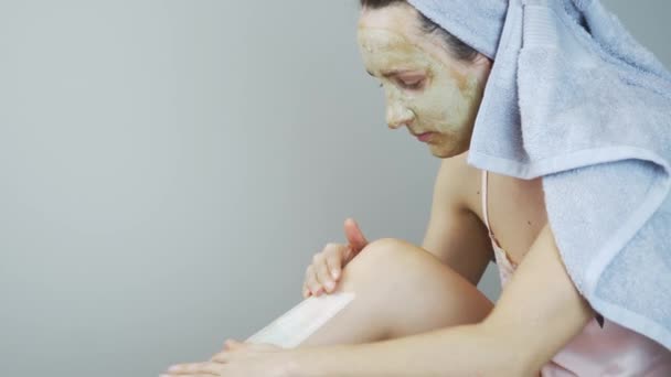 Processus de dépilation. Femme en lingerie et serviette sur la tête après la douche faire épilation sur les jambes avec des bandes de papier spécial. Jambes épilatoires féminines avec de la cire. Fille enlever les cheveux sur les jambes à l'aide de cire — Video