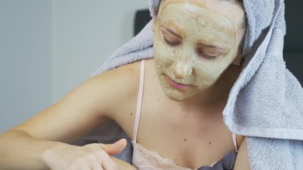 Portrait of woman with face mask and towel on head doing leg epilation and feeling pain. Female after spa having hair removing procedure on legs with wax. Depilation on legs with special paper strips — Stock Video