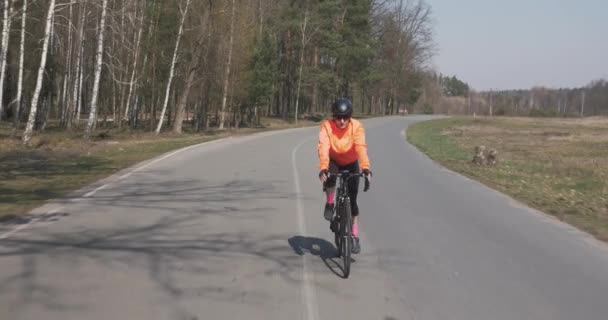 ロードバイクで女性のトライアスロンサイクリング。女性は空の道路で自転車に乗る。女の子は自転車に乗っている。サイクリングとトライアスロンのコンセプト — ストック動画