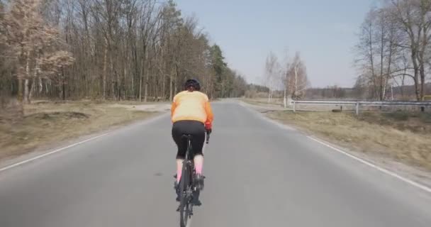 Vrouw rijdt op de fiets. Vrouwelijke fietsen op de fiets. Triatleet hard trappen op de fiets. Meisje in helm rijden buiten. Triathlon-concept — Stockvideo