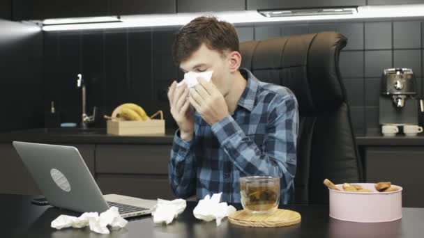 鼻水の多い男が家から働いている。職場で咳をしている男はいない。フリーランスの病気や悲惨な探しています。自宅のオフィスで働いている病人。冷たい咳やくしゃみをする人 — ストック動画