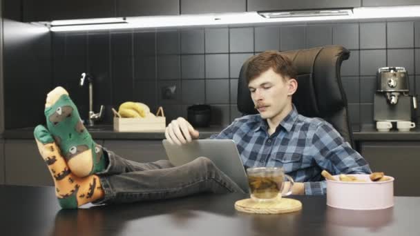 Egy alkalmi férfi laptopon dolgozik otthon. A férfi szabadúszó laptopot használ a konyhában. Happy személy dolgozik online laptop otthoni iroda — Stock videók
