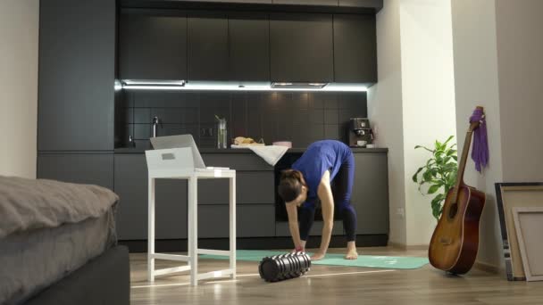 Chica haciendo ejercicios de fitness en línea en la cocina en casa. Mujer fuerte confianza en el entrenamiento de ropa deportiva atlética y estiramiento en casa utilizando cursos aeróbicos en línea para las mujeres en el ordenador portátil — Vídeos de Stock