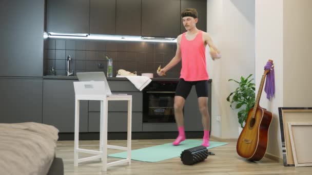 Veselý mladý muž s knírkem a růžovým oblečkem z 80. let, cvičí s použitím banánů místo činek. Legrační mužský atlet sledování on-line fitness tříd a dělat aerobní cvičení — Stock video