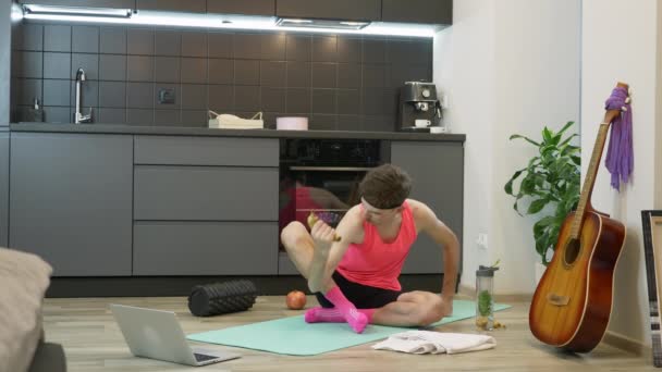 Grappig uitziende jongeman met snor en roze sportkleding doet workout oefeningen met bananen en zoenen biceps. Kerel training thuis tijdens coronavirus quarantaine. Online fitness oefeningen — Stockvideo