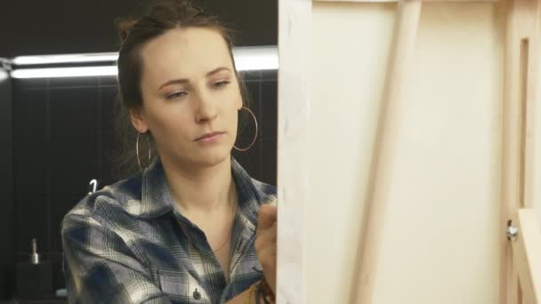 Mujer sonriente inspirada dibuja cuadro sobre lienzo, de cerca. Joven pintura femenina en casa. Inspiración. Escuela de dibujo. Casa terapia de arte — Vídeos de Stock