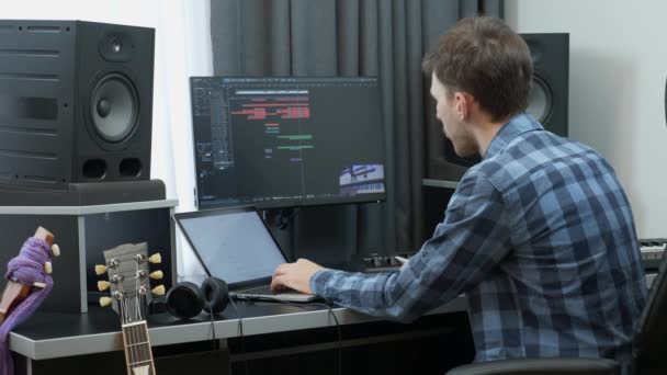 Productor de música mezclando y masterizando la canción pop rock hit en el estudio de grabación de música en casa con monitores y computadora — Vídeo de stock