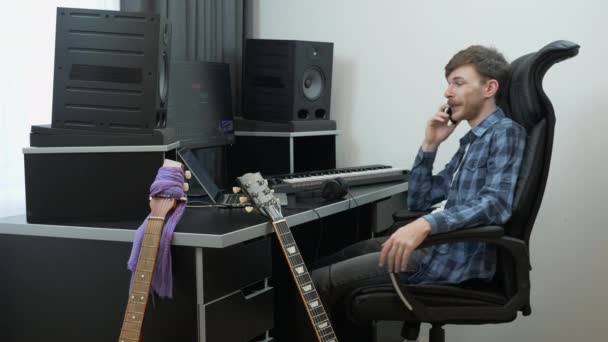 Ο συνθέτης μουσικής ήχου μιλάει στο τηλέφωνο στο στούντιο ηχογράφησης του σπιτιού σχετικά με το συμβόλαιο μουσικής με τον πελάτη. Μουσική έννοια στούντιο ηχογράφησης — Αρχείο Βίντεο