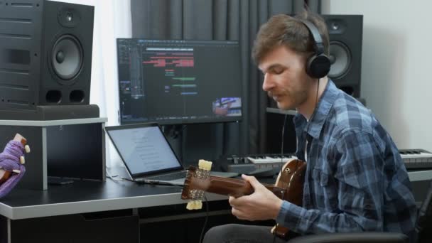 Guitarrista grabando y tocando la guitarra en el estudio de música de grabación en casa. Joven artista tocando la guitarra en casa . — Vídeo de stock