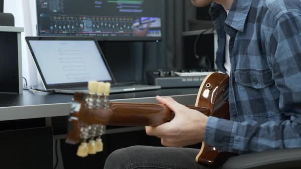 Homem tocando e gravando guitarra solo em casa estúdio de gravação em frente ao computador portátil e equipamento de engenheiro de som. — Vídeo de Stock