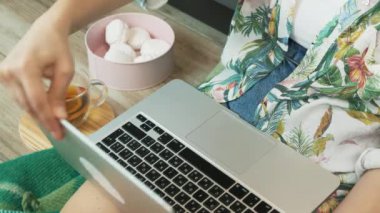 Evden internetten kadın milenyum araştırması. Genç kız dizüstü bilgisayarı açıyor ve klavyede daktilo kullanıyor. Gençler izolasyon sırasında arkadaşlarıyla çevrimiçi sohbet ediyorlar. Dizüstü bilgisayarda çalışan kadın