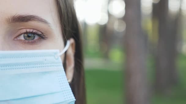 Retrato de una joven mujer hermosa se quita la máscara protectora de la cara médica durante la cuarentena. Chica que usa máscara azul médica para la prevención y protección de infecciones por virus. Pánico de virus epidémicos, miedos — Vídeos de Stock