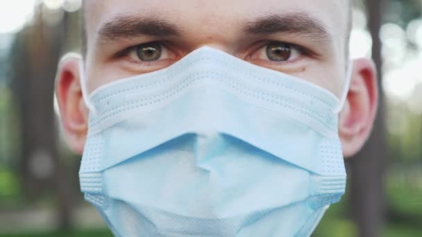 Boldog mosolygós fiatalember leveszi védő orvosi maszkot a koronavírus covid-19 járvány után. Egy férfi arcképe, amint orvosi kék maszkot vesz le és mosolyog. Vírusfertőzés megelőzése és védelme — Stock videók