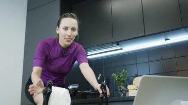 Sportif kız, evdeki akıllı bisiklet eğitmeninde sıkı antrenman ve fitness kardiyo çalışmasından sonra havluyla yüzünü ovalıyor. Evde bisiklete binerken yüzünü havluyla silen kadın.