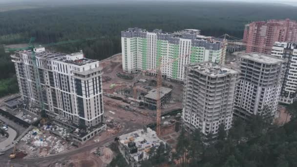 Vista aérea do drone do canteiro de obras com guindaste alto. Local de construção com altos apartamentos residenciais modernos em área verde cercada por floresta. Construir os edifícios. Processo de construção — Vídeo de Stock