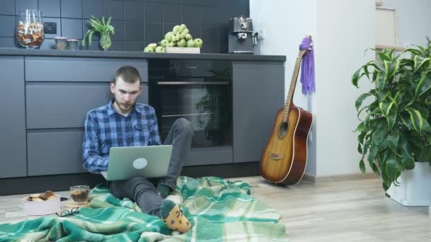 피곤 한 젊은 남자 가집에서 일 한 후에 노트북 컴퓨터를 닫는다. 집에서 컴퓨터를 사용하는 남성, 바이러스가 창궐하는 동안 혼자 격리되어 있습니다. 아늑 한 녹음실 집에서 노트를 만들고 있는 사람 — 비디오
