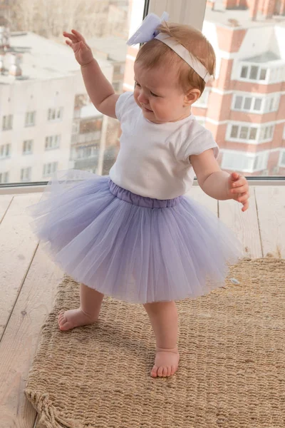 Una linda niña en un tutú de ballet lila está junto a la ventana y llora — Foto de Stock