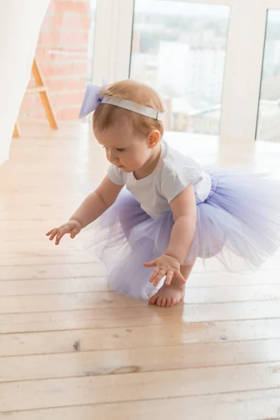 Милая маленькая девочка в сиреневой балетной пачке сидит на полу Лицензионные Стоковые Изображения