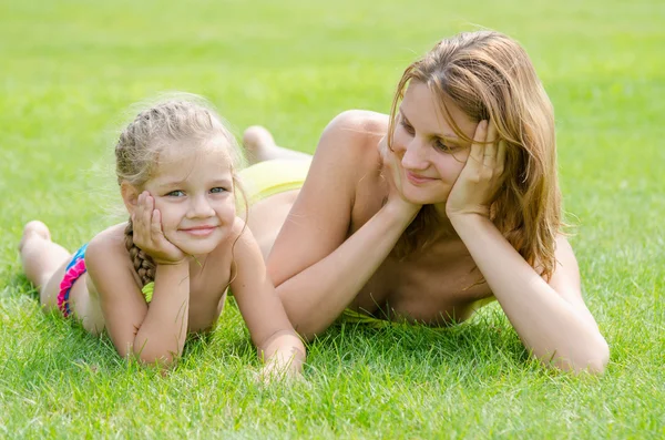 Jeune mère couchée sur l'herbe verte et regardant sa fille de cinq ans qui est couché près — Photo