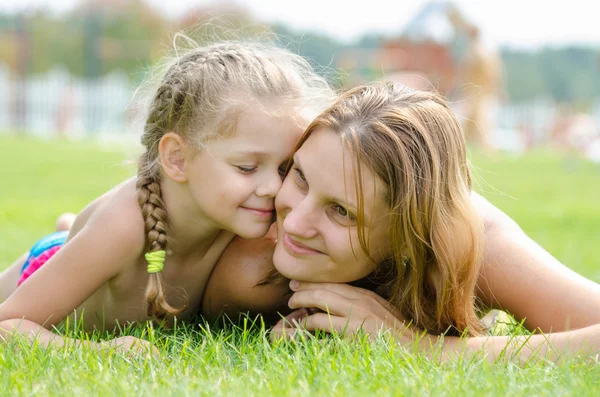 Cinco años linda hija presionó su cara a la cara de la madre en un césped de hierba verde — Foto de Stock