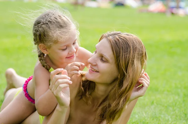 Moeder en dochter plezier liggend op een groen gazon in de zomer — Stockfoto