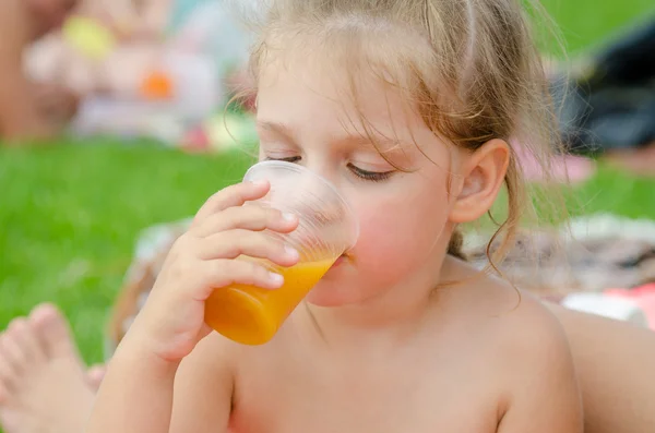 Девушка пьет фруктовый сок из пластиковой одноразовой чашки — стоковое фото