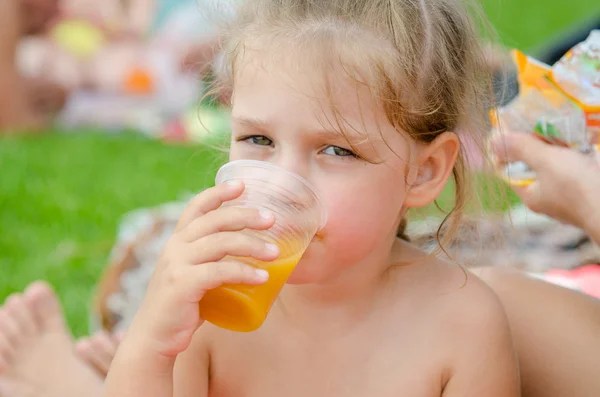 Flicka dricka frukt juice från en disponibel plastmugg och såg i ramen — Stockfoto