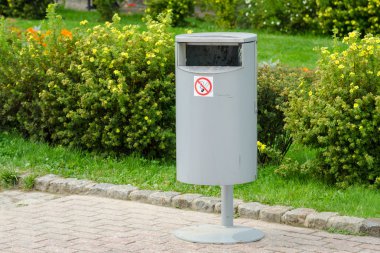 Doğru silindirik metal çöp kutusu arka plan bakımlı çim üzerinde