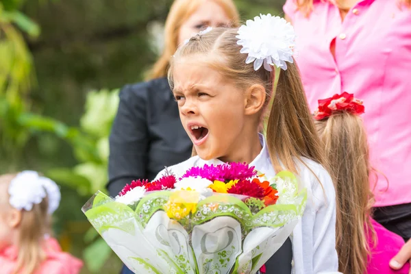 Il primo alunno con un mazzo di fiori sbadiglia a scuola in mezzo alla folla — Foto Stock