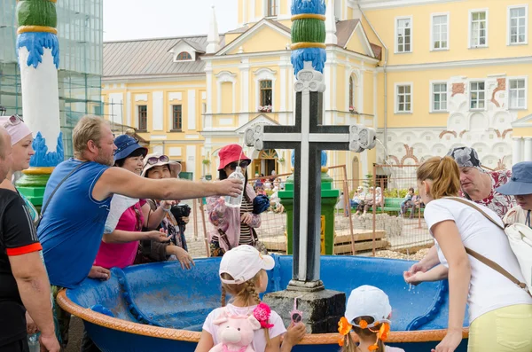Sergiev Posad - August 10, 2015: Tourists are gaining the holy water in the passage of the bowl with a cross in Svvyato Trinity St. Sergius Lavra — Stock Photo, Image