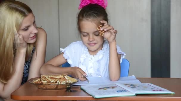 Семирічна школярка, яка їсть домашню печінку, розповідає мамі про домашнє завдання — стокове відео