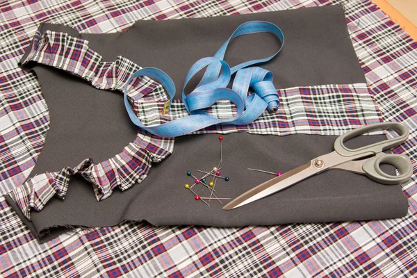 Вид сверху детского заготовки школьного платья, лежащего на столе со швейными принадлежностями — стоковое фото