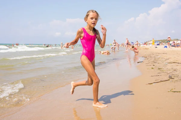 Siete años chica corre en la playa desde el mar — Foto de Stock