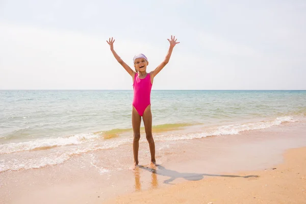 Счастливая девушка подняла руки на песчаный берег моря — стоковое фото