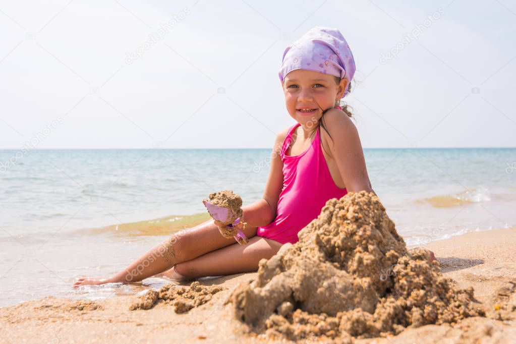 The baby digs a shovel sand sitting on the beach