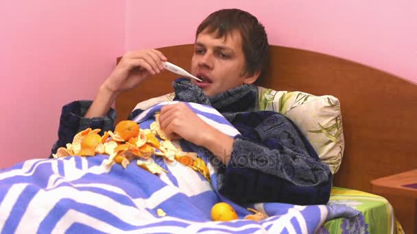 Um homem doente deitado na cama e medirá a temperatura de um termômetro eletrônico — Vídeo de Stock