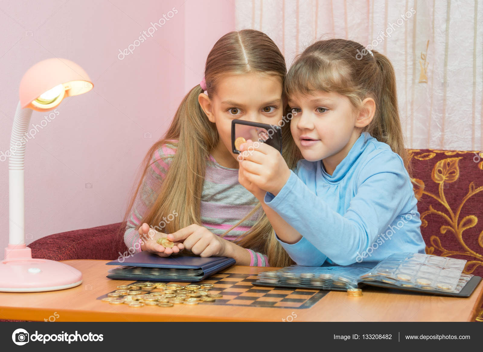 Due bambini stanno guardando una moneta attraverso una lente di ingrandimento — Foto Stock