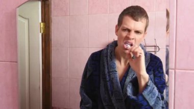 genç adam banyoda Dişlerini fırçalıyor화장실에서 그의 솔 질 하는 젊은이