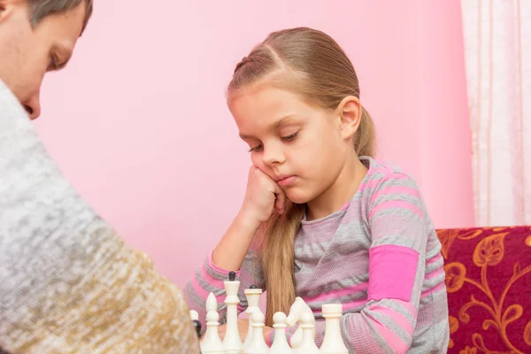 Sjuåriga dotter funderar på nästa drag, spela schack — Stockfoto