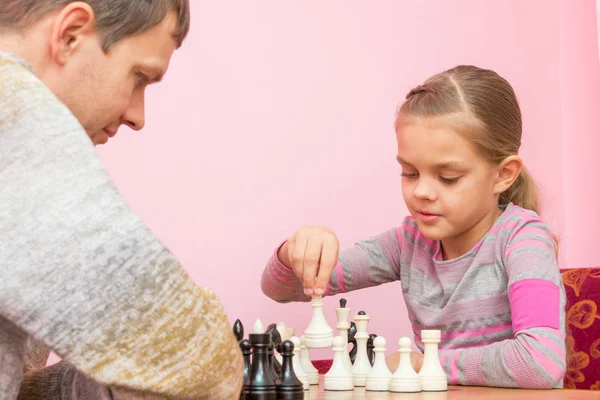 女孩在和教练下棋的时候做出下一个动作 — 图库照片