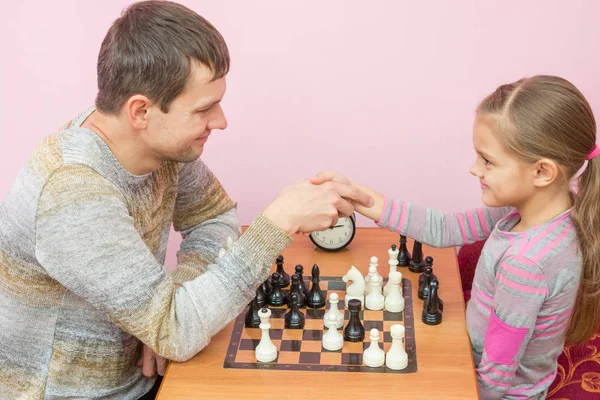 Папа и дочь пожали друг другу руки, играя в шахматы — стоковое фото