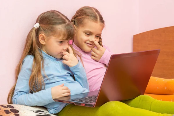 Två tjejer plocka hans näsa och tittar på en laptop skärm — Stockfoto