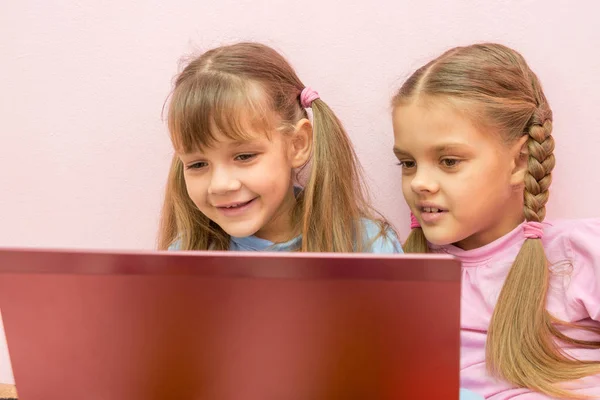 Twee meisjes kijken naar laptop en glimlachen — Stockfoto