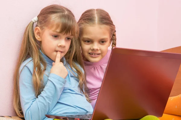 Grappig meisje met een vinger in zijn mond zit op een laptop — Stockfoto