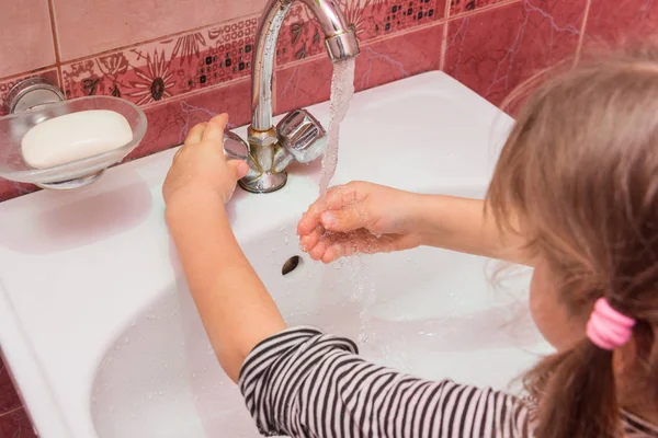 Ragazza di cinque anni regola il flusso e la temperatura desiderati dell'acqua che scorre dal rubinetto nel lavandino — Foto Stock