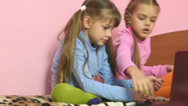 Två flickor att välja att se i en laptop — Stockvideo