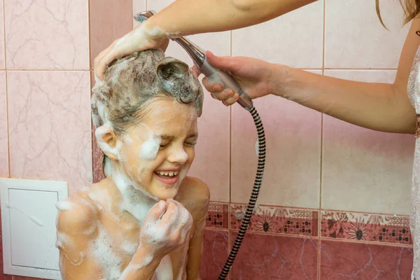 Mamá lava el jabón y el champú en la ducha con una hija de siete años — Foto de Stock