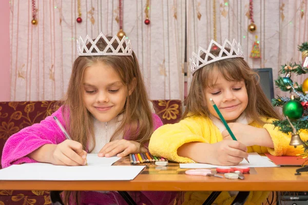 Två flickor gärna skriva ett brev till jultomten som sitter vid ett skrivbord i hemmiljö — Stockfoto