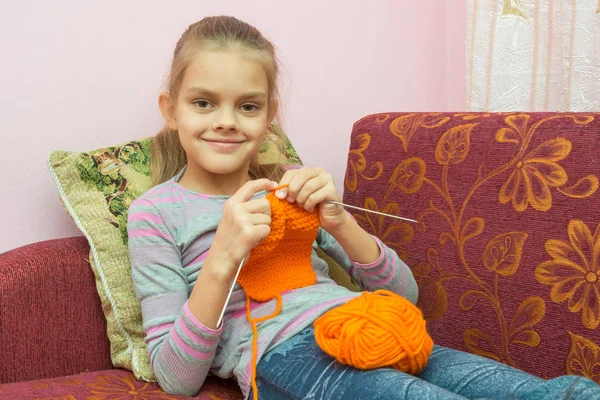 Girl sitting on the couch, knits on the needles, and looked into the frame — Stock Photo, Image